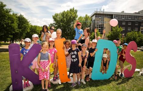 Children posed around "Kids" sign. 